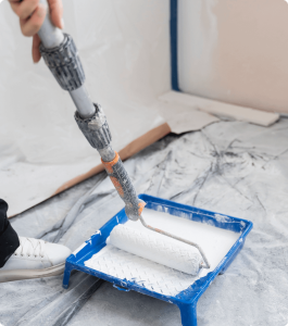 A person painting a wall with a roller, a common budget-friendly home renovation project that can increase a property's value.